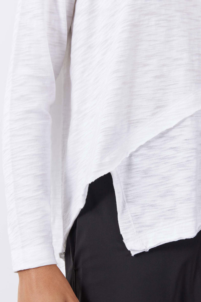 White long sleeve top detail, asymmetrical drape and curved hem opening