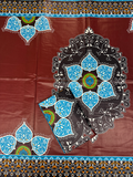 a dark reddish-brown base with a large black mandala-style floral motif outlined in white, bright blue petal shapes, and small green accents. Decorative borders repeat along the top and bottom edges.
