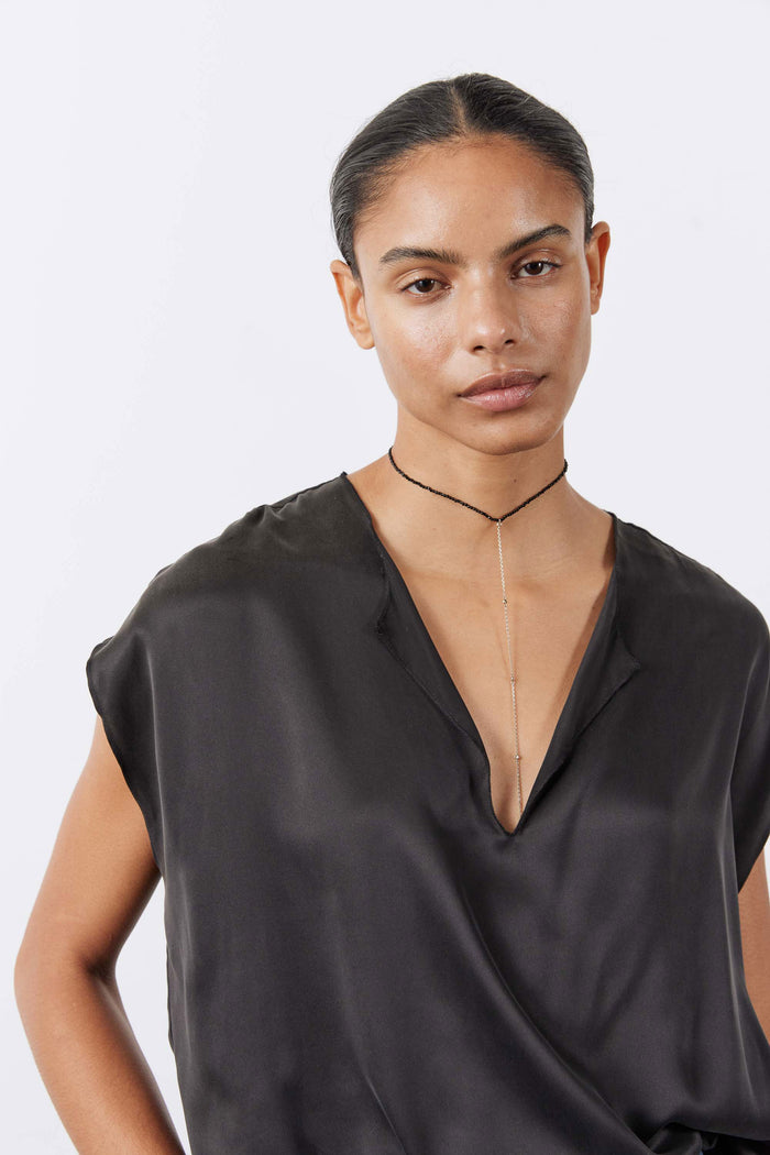 Black silk V-neck top with short sleeves, close-up of neckline and sheen